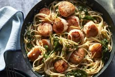 pasta with scallops and spinach in a skillet on a gray surface