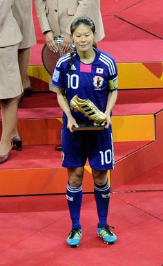 a woman holding a soccer ball and glove on top of a red carpeted floor