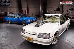 two cars parked in a garage with their hoods open and engines on the hood