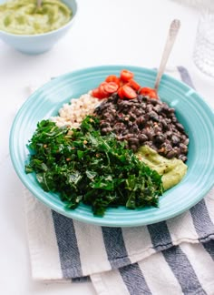 a blue plate topped with beans, rice and greens