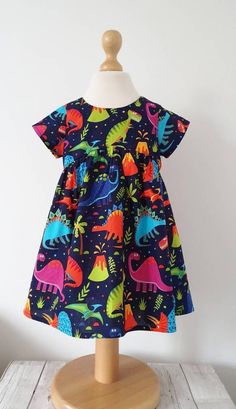 Stunning dinosaur dress. Set on a navy background filled with bright coloured dinosaurs. 100% cotton.The bodice is fully lined with polycotton. Cute cap sleeves & lightly gathered skirt.This is my best selling style dress ***Measurements are as follows***Newborn Height 22" chest 16" Waist 16.25"3-6 months Height 25" chest 17.25" Waist 17"6-9 months Height 28"chest 18.5" Waist 17.75"12-18 months Height 32" chest 19.75" Waist 18.5"Age 2 Height 36" chest 21.25" Waist 20"Age 3 Height 38.5" chest Dinosaur Fashion, Dino Outfit, Dino Dress, Etsy Clothing, Dinosaur Dress, Keep Strong, Etsy Clothes, Cute Cap, Kam Snaps