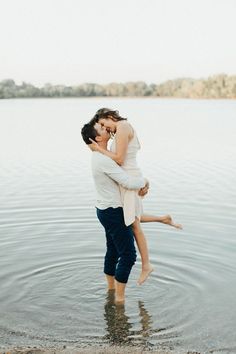 a man holding a woman in his arms while standing in the water with an instagram button