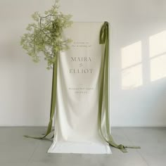 a white chair with a green ribbon tied around it and a bouquet of flowers on the back