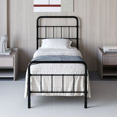 a black metal bed frame in a bedroom with white walls and carpeted flooring