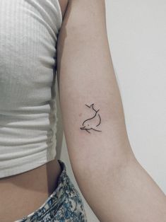 a woman's arm with a small bird tattoo on the left side of her arm