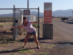 a woman leaning against a fence with her arms outstretched