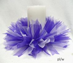 a white candle with purple tulle around it