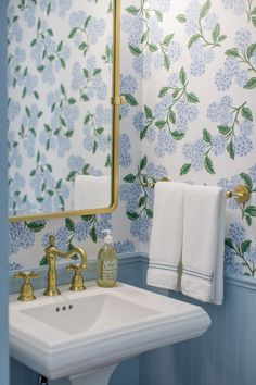 a white sink sitting under a bathroom mirror next to a wall mounted faucet