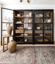 a room with some vases and other items on display in the glass doorsed cabinet