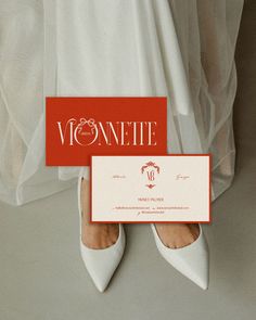 a woman in white shoes holding up a business card with the word womenite on it