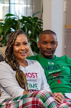 a man and woman are sitting on a couch smiling at the camera while wearing matching pajamas