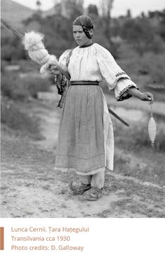 an old black and white photo of a woman holding a bird in her hand while standing on a dirt road