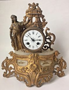 an antique clock with statues on it against a white background and the time is 11 00