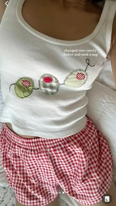 a woman laying on top of a bed wearing red and white checkered shorts with buttons