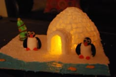 an igloose with two penguins in front of it and a christmas tree