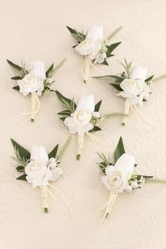 wedding bouquets with white flowers and greenery laid out on the wall for decoration