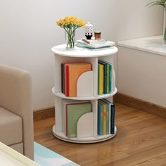 a white table with books and flowers on it in the corner of a living room