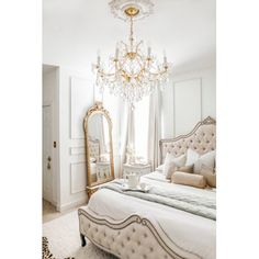 a bedroom with a bed, chandelier and mirror