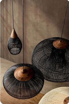 three hanging lamps made out of wickers and wood, on a wooden table