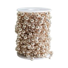 a spool of beaded wire on a white surface with silver balls and beads