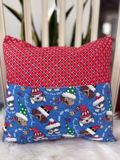 a red and blue pillow sitting on top of a white chair next to a potted plant