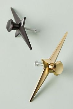 two gold and black metal objects on a white surface with screws in the shape of an airplane