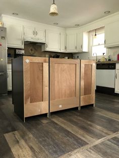 a kitchen with white cabinets and wood flooring in the middle, an island is built into the wall