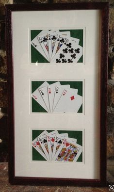 four playing cards are displayed in front of a stone wall with a wooden frame on it