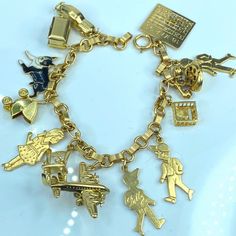 A Modernist 14k Yellow Gold Charms In Fancy Charm Bracelet Starter. It Suspends Twelve (12) 14k Yellow Gold Charms, Hallmark Or Tested. They Are: Mechanical Old Fashioned Luxury Car With Moving Wheel Mechanical Treasure Chest With Lid Able To Open, A Pearl Inside Enamel French Bull Dog Mechanical Baby Stroller, Movable Wheel With Movale Canopy Young Girl With Insignia Rocking Chair Mechanical Jet Plane With Movable Wheel Young Boy Charm With Insignia Young Boy Charm With Insignia Baby Playpan Me Gold Charms, French Bull, Jet Plane, Baby Stroller, Luxury Car, Sapphire Stone, Treasure Chest, Gold Enamel, Gold Charm