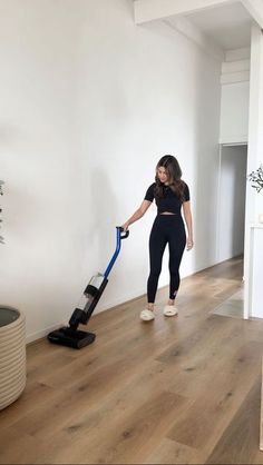 a woman is cleaning the floor with a vacuum