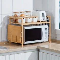 a microwave oven sitting on top of a wooden shelf next to a counter filled with food