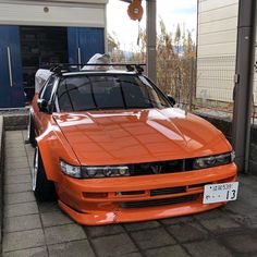 an orange car parked in front of a garage