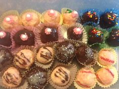 there are many different types of chocolates in the tray on the table, including one with frosting and one with sprinkles