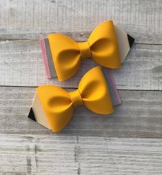 two yellow bow ties on top of each other in front of a wooden background with planks