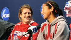 two women in red and gray hoodies talking to each other while holding microphones