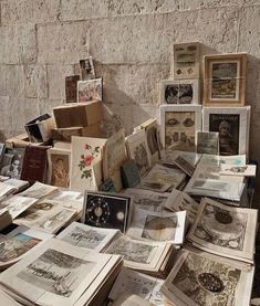 many old books are stacked on top of each other in front of a stone wall