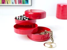 two red containers with rings on them sitting next to a key chain and ring holder