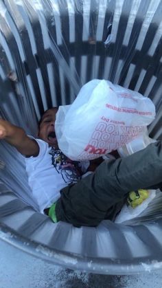 a young child is laying in a trash can