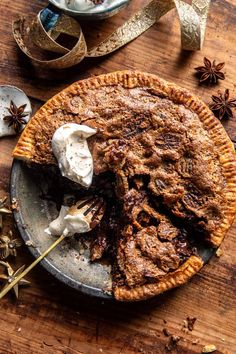 a pie on a wooden table with an assortment of toppings and spices around it