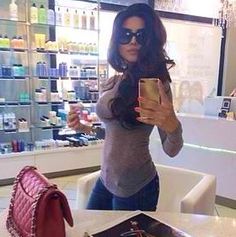 a woman taking a selfie with her cell phone in front of a store counter