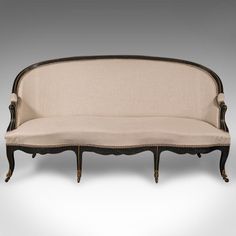 an antique style couch with black trim and beige upholstered fabric on the back