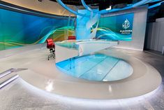 an empty television studio set with blue and green swirls on the wall behind it