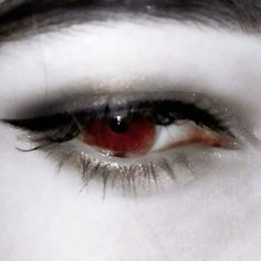 the eye of a woman with red eyeshade and black lashes is seen in this close up photo