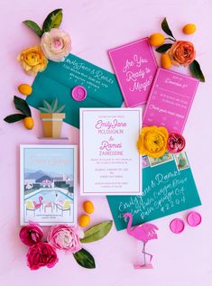 the wedding stationery is laid out on pink and blue paper with flowers, cards, and envelopes