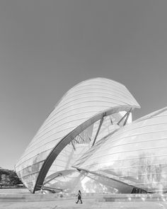 black and white photograph of people walking in front of an architectural building with curved roof