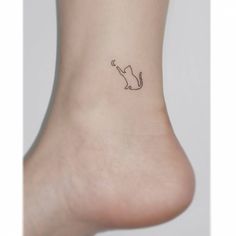 a small cat tattoo on the side of a woman's foot, which is black and white