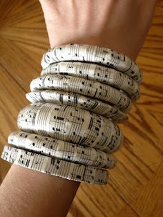 a woman's arm with four bracelets made out of sheet music notes