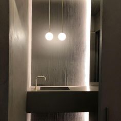 a bathroom with two lights hanging from the ceiling and a sink in front of it