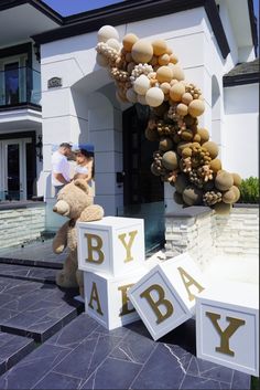 two people are standing in front of a house with balloons and teddy bears on it