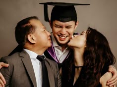 a man and woman kissing each other in front of a graduation cap on their head